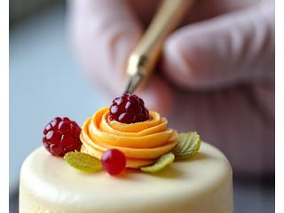 Pastry chef adding delicate final touches to a decorated cake with a small palette knife, focusing on fine details.