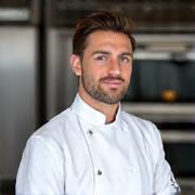Portrait of Pastry Chef Ben Carter, with a focused expression, in a pristine chef's uniform.