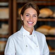 Portrait of Artisan Bread Specialist Sophia Khan, with warm eyes and a pleasant smile.
